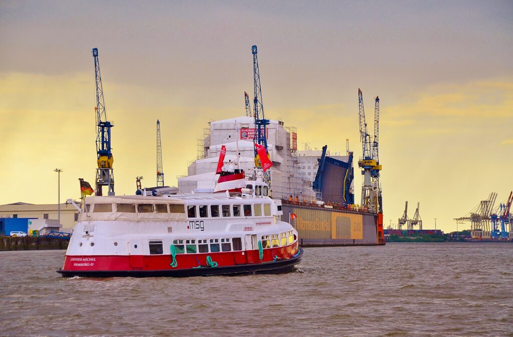 Die Hafenfähre Grosse Michel fährt gegen Sonnenuntergang im Hamburger Hafen am Werft von Blohm und Voss vorbei.