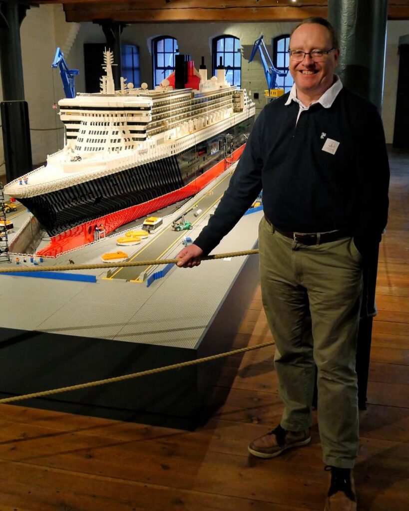 Der Marinearchiteckt der QM2, Stephen Payne, und die Queen Mary 2 aus Lego auf Deck 1. Sommer 2018.