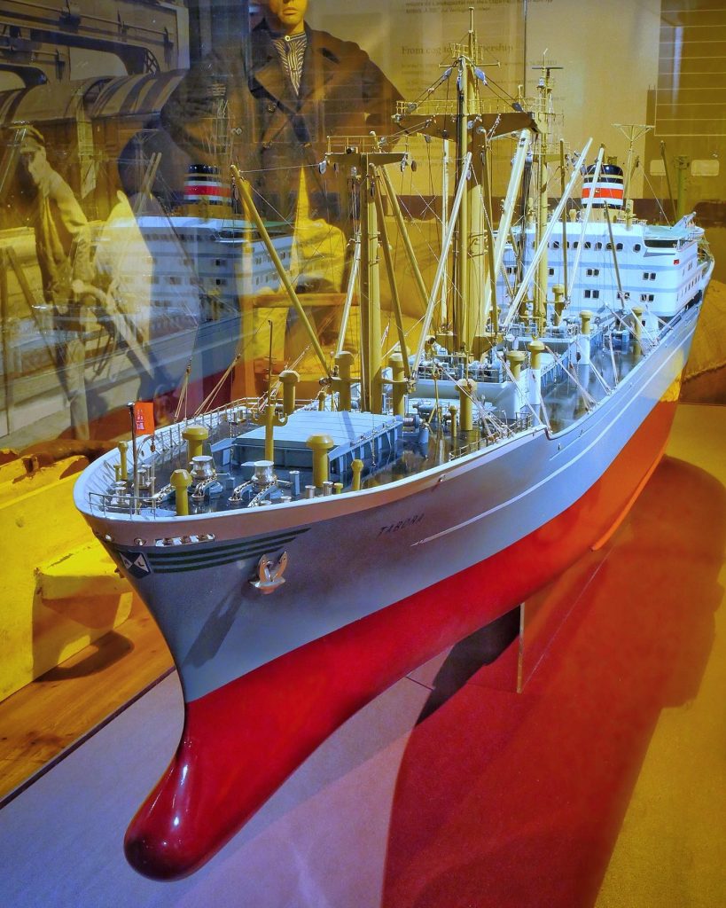 Der Stückgutfrachter MS Tabora (1965-1987). Ihr Original-Werftmodell wurde in der Werkstatt von Ihlenfeld & Berkefeld im Maßstab 1:100 gebaut und ist Teil unserer Ausstellung über die Geschichte der modernen maritimen Logistik. Sie befindet es auf Deck 6 des Museums. Ihre Baupläne befinden sich in unserem Archiv.