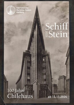 Sepiafarbenes Plakat mit frontal aufgenommener, spitz zulaufender Ansicht des Chilehauses in Hamburg, das wie ein Schiffsbug wirkt, rechts der Titel „Schiff aus Stein“, oben links das Logo des Internationalen Maritimen Museums, unten der Schriftzug „100 Jahre Chilehaus“ und das Datum „ab 15.11.2024“.