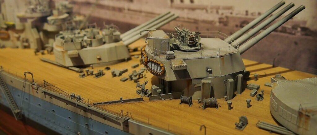 Detailliertes Modell eines Schlachtschiffs mit Holzdeck, mehreren Geschütztürmen und feinen Decksdetails.