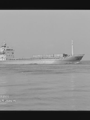 Frachtschiff seitlich auf ruhiger See, Schwarzweißaufnahme mit Schriftzug Internationales Maritimes Museum Hamburg unten links.
