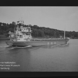 Frachtschiff mit großen Aufbauten und Schriftzug BBR fährt auf einem Fluss, bewaldetes Ufer im Hintergrund.