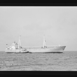 Frachtschiff mit zwei Masten und kleinem Schlepper bei ruhiger See; Wasserzeichen des Maritimen Museums.