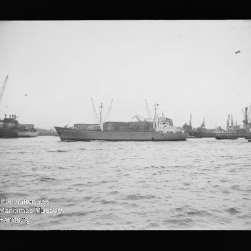 Frachtschiff im Hafen vor Kränen auf rauer See; Stempel Internationales Maritimes Museum Hamburg.