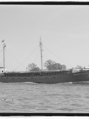 Frachtschiff mit zwei Masten fährt über ruhiges Wasser; schwarzweißes Foto mit Museums-Wasserzeichen.