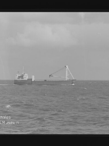 Frachtschiff mit großem A‑Rahmen-Kran auf ruhiger See unter bewölktem Himmel
