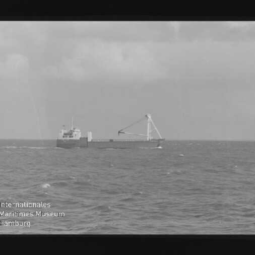 Frachtschiff mit großem A‑Rahmen-Kran auf ruhiger See unter bewölktem Himmel