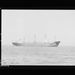 Seitenansicht eines Frachtschiffs auf ruhiger See; sichtbares Wasserzeichen: Internationales Maritimes Museum Hamburg.