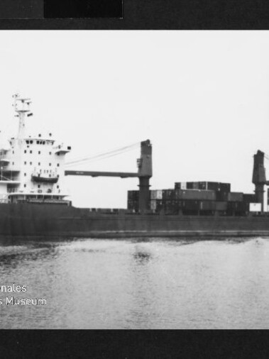 Frachtschiff mit Containern und zwei Ladekränen auf ruhigem Wasser; Wasserzeichen des Maritimen Museums Hamburg unten links.