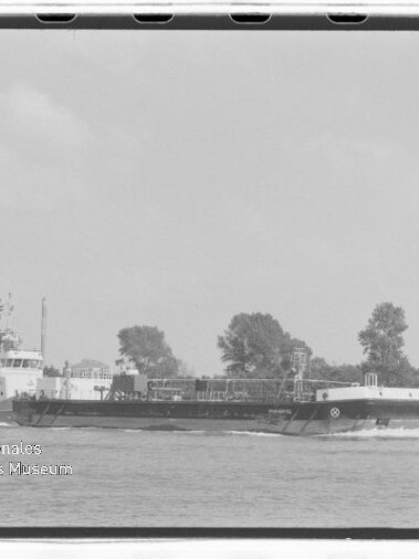 Schwarzweißaufnahme eines langen Tankbarges auf einem Fluss vor Bäumen; links Wasserzeichen Maritimes Museum Hamburg.