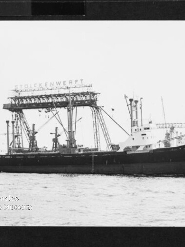 Frachtschiff mit hohem Portalkran an Bord und großem Schriftzug 