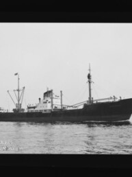 Seitliches Profil eines Frachtschiffs auf ruhiger See mit Masten, Ladebaum und Flagge; Museumslogo unten links