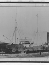 Historisches Dampfschiff Bürgermeister Petersen mit Schornstein und hohen Masten am Ufer, schwarzweiß.