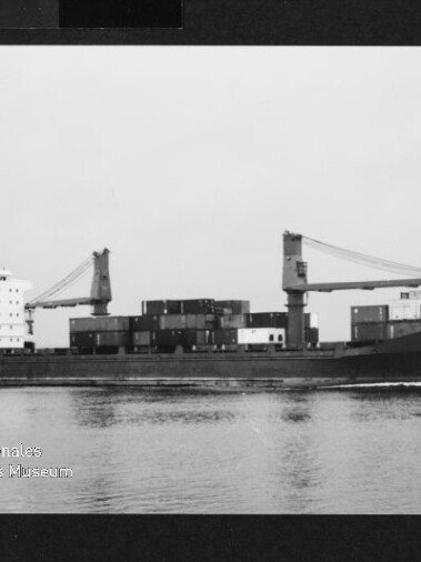 Frachtschiff ACTUARIA mit aufgestapelten Containern und zwei Ladekränen fährt auf ruhiger See, Museumslogo unten links.