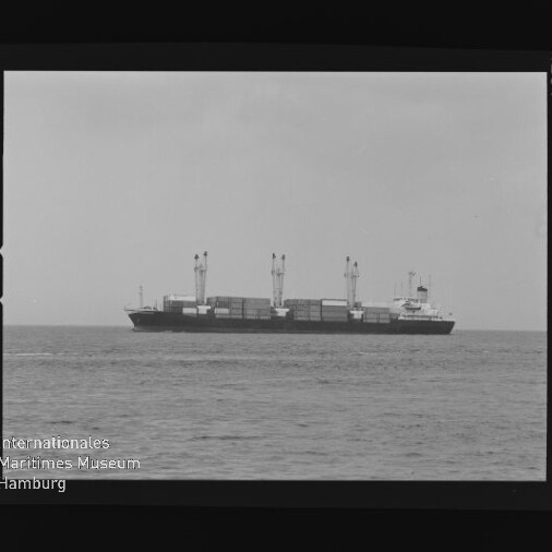 Containerschiff mit Ladekränen auf ruhiger See, mittig im Bild, umrahmt von Filmrand mit AGFA-Schrift und Museumssiegel.