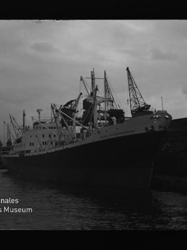 Großes Frachtschiff am Kai, mehrere Ladekräne im Hafen; Schriftzug Internationales Maritimes Museum Hamburg links unten.