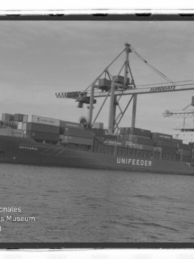 Containerschiff UNIFEEDER am Kai, beladen von großen Hafenkränen mit aufgetürmten Containern.