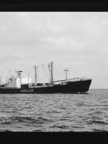 Schwarzweiß-Aufnahme eines Hapag‑Lloyd Frachtschiffs auf ruhiger See unter bewölktem Himmel, Museumswasserzeichen links unten.