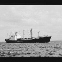 Schwarzweißes Frachtschiff mit Hapag-Lloyd-Schriftzug auf ruhiger See, Museumswasserzeichen unten links.
