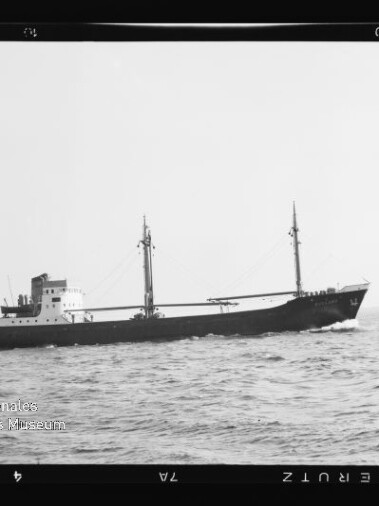 Frachtschiff auf ruhiger See in Schwarzweiß, seitliche Ansicht mit Internationales Maritimes Museum Hamburg-Wasserzeichen.