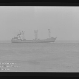 Frachtschiff mit drei Kränen bei diesigem Horizont; unten links Logo und Schriftzug 'Maritimes Museum Hamburg'.