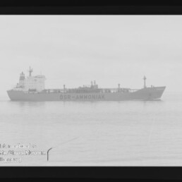 Schwarzweiß-Filmaufnahme eines Tankschiffs mit der Aufschrift DSR-AMMONIAK auf ruhiger See, sichtbarer Filmrand und Museumswasserzeichen.