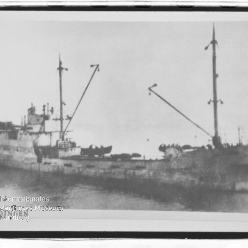 Altes Frachtschiff mit zwei Masten und schrägen Ladebäumen, sichtbares Museumswasserzeichen unten links.
