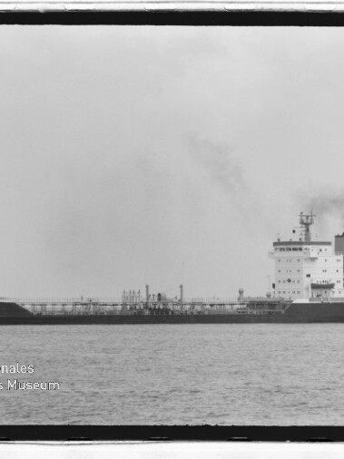 Schwarzweißfoto eines Tankschiffs mit Namen BUTT, rauchender Schornstein auf ruhiger See; Museumslogo unten links.