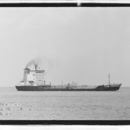 Schwarzweißaufnahme eines Tankers mit der Aufschrift TTUB am Bug, rauchendem Schornstein auf offener See.