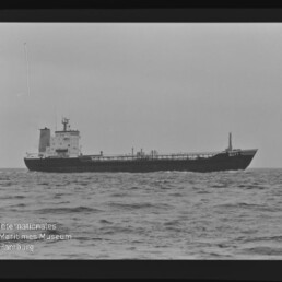 Tankerschiff auf ruhiger See in Schwarzweiß, mit sichtbaren Rohrleitungen und dem Namen GULF am Bug.