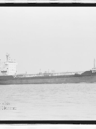 Schwarzweißfoto eines Tankschiffs mit Namen BUTT auf ruhiger See, Museumswasserzeichen unten links.