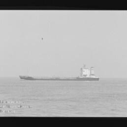 Tankerschiff in der Ferne auf ruhiger See, sichtbarer schwarzer Filmrand und Wasserzeichen des Internationalen Maritimen Museums Hamburg.