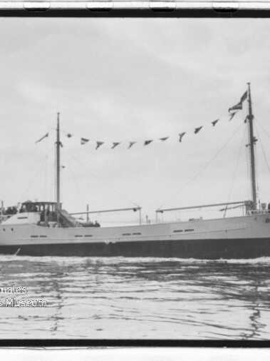 Schwarzweißaufnahme eines zweimastigen Schiffes mit Wimpelgirlande, das ruhig auf glattem Wasser fährt.
