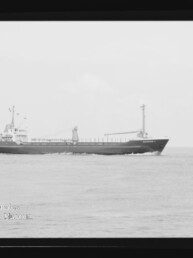 Schwarzweiß-Seitenansicht eines Frachtschiffs auf ruhigem Meer mit Brücke achtern und Ladekran, Museumswasserzeichen unten links.