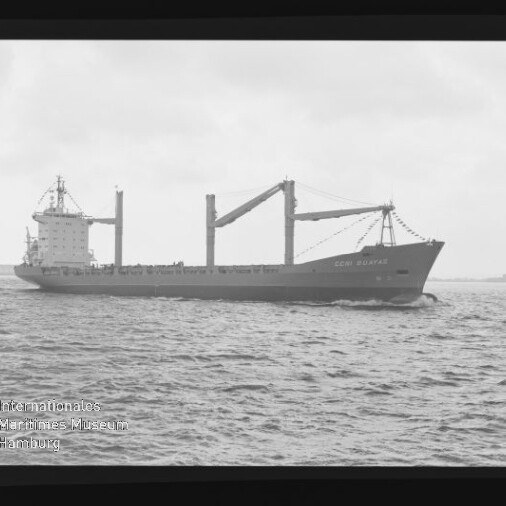 Schwarzweiß-Foto eines Frachtschiffs mit zwei Deckskränen, seitlich über ruhiger See, Filmrand und AGFA-Schrift sichtbar.
