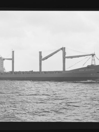 Frachtschiff seitlich mit drei Deckskranen, Aufbauten achtern und Girlanden am Bug; Wasser und Museumswasserzeichen.