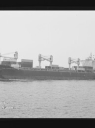 Schwarzweiß-Foto eines Frachters mit Deckkränen und Containern auf ruhiger See, sichtbar filmrand und AGFA PAN 100-Markierung.