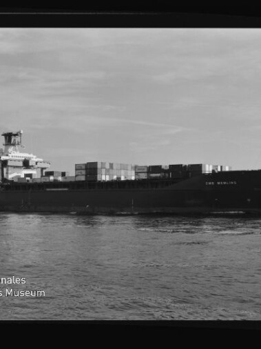 Containerschiff mit Containern auf ruhigem Wasser; links unten Wasserzeichen Internationales Maritimes Museum Hamburg.