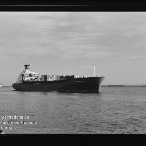 Containerschiff mit aufgestapelten Containern auf ruhiger See vor flacher Küste, Museumslogo links unten.