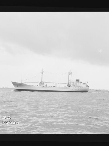 Großes Frachtschiff mit Deckaufbauten und Ladekränen auf ruhiger See, daneben ein Motorboot und ein Segelboot; Wasserzeichen Internationales Maritimes Museum Hamburg