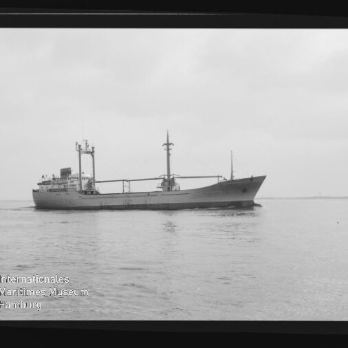 Frachtschiff mit zwei Masten und Ladegeschirr fährt auf ruhigem Wasser; Museumslogo unten links sichtbar.