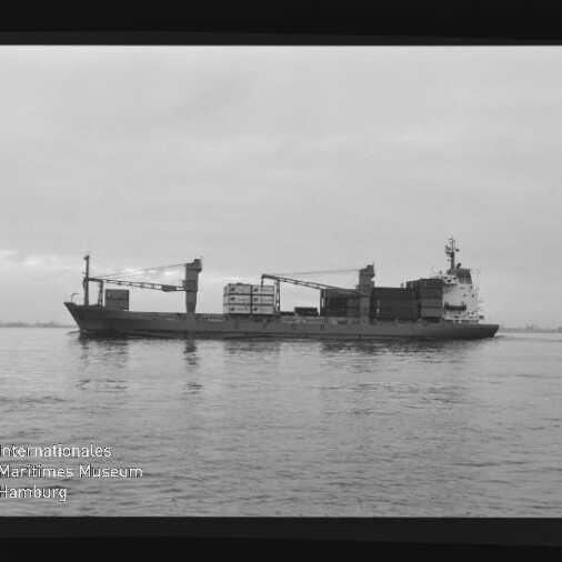 Frachtschiff mit Ladekränen und Containern auf ruhiger See, Museumslogo unten links.