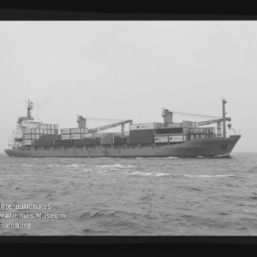 Frachtschiff mit gestapelten Containern und zwei Ladekränen auf ruhiger See, schwarz-weißes Foto.