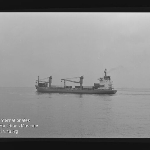 Frachtschiff mit Ladekränen auf ruhiger See, Schwarzweiß-Negativ mit Filmrand-Beschriftung AGFA PAN 100 und Museumslogo