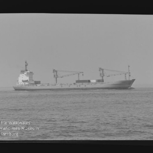 Frachtschiff mit zwei Ladekränen auf ruhiger See, schwarzweißes Foto mit Wasserzeichen Internationales Maritimes Museum Hamburg