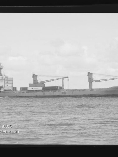 Frachtschiff mit zwei Ladekränen auf ruhiger See in s/w, mit schwarzem Negativrand und Wasserzeichen Maritimes Museum Hamburg.