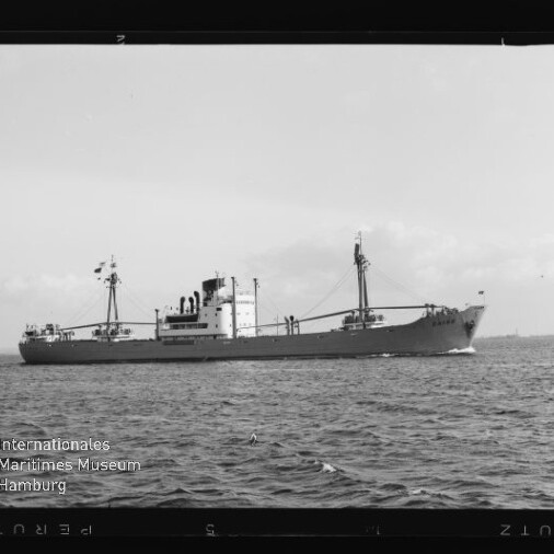 Frachtschiff in Seitenansicht auf ruhiger See mit Mast und Ladebaum, Museumslogo unten links.