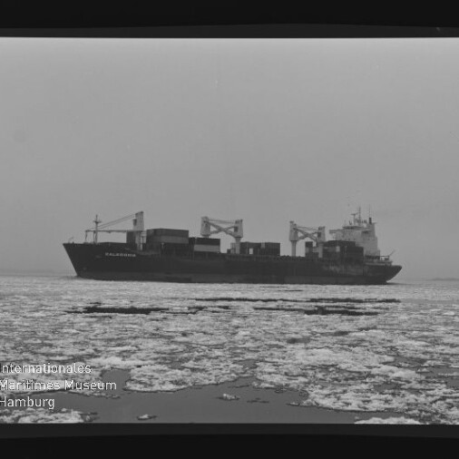 Frachtschiff mit Ladekränen auf eisbedecktem Meer, Eisschollen im Vordergrund, Schwarzweißaufnahme mit Museumswasserzeichen