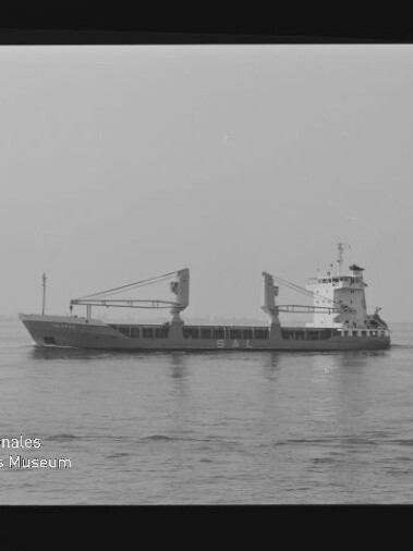 Frachtschiff mit zwei Ladekränen auf ruhiger See, seitliche Schwarzweißaufnahme mit flachem Horizont.